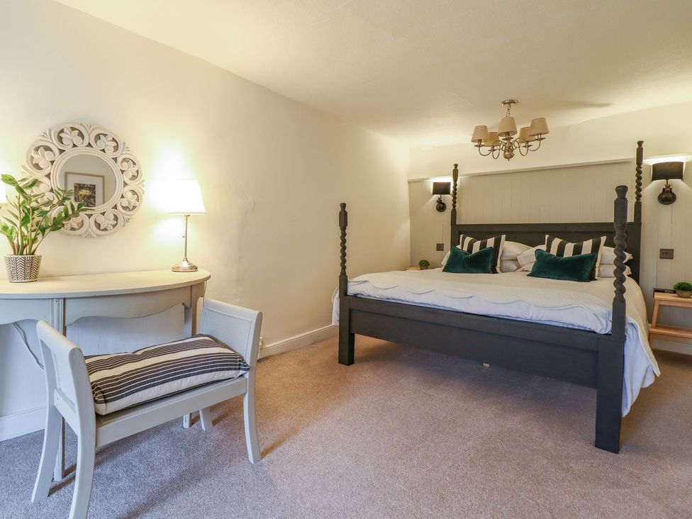 A bedroom with a bed and table at Bwthyn Canol in Llanfair