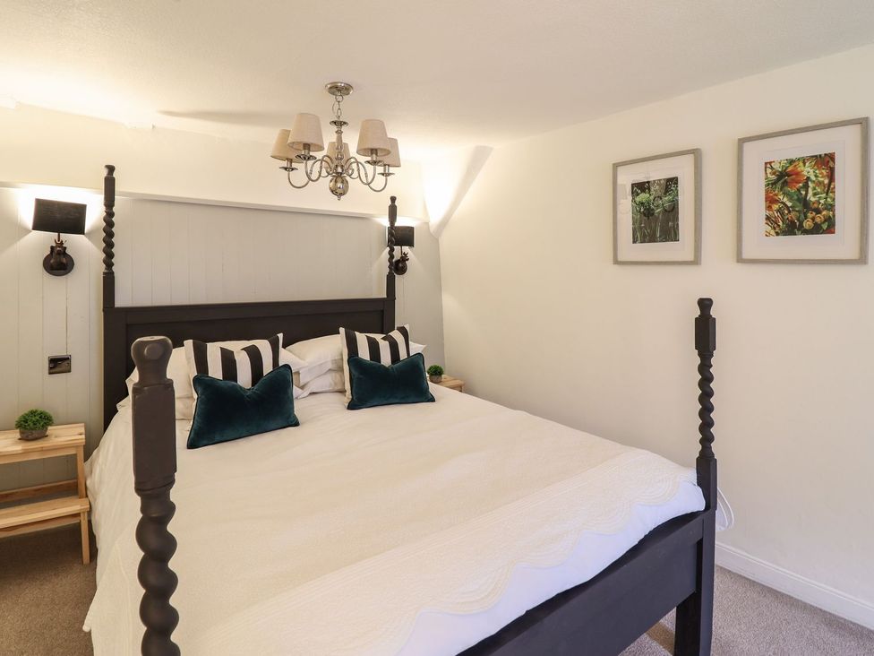 A bedroom with a bed and framed pictures at Bwthyn Canol in Llanfair