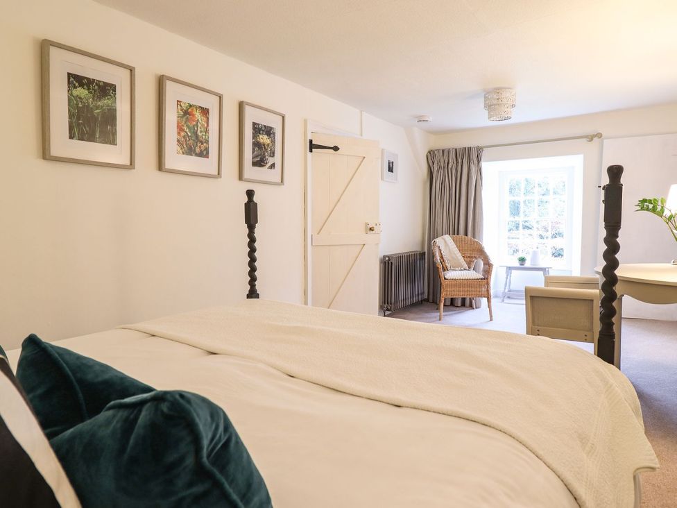 A bedroom with a bed and chair at Bwthyn Canol in Llanfair