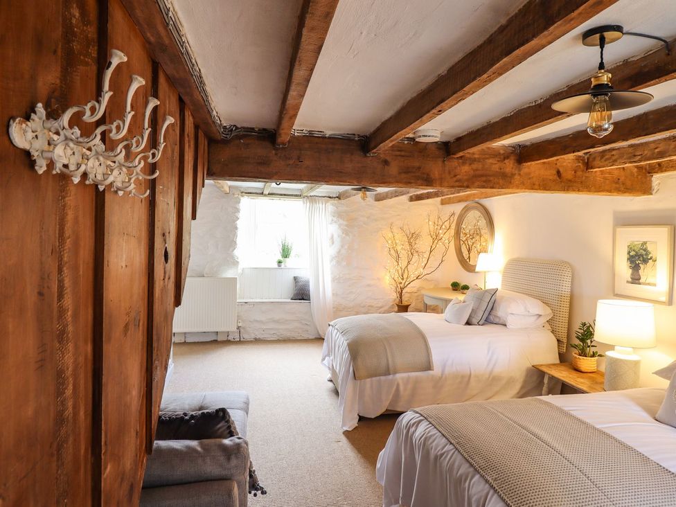 A bedroom with two beds and a decorative branch at Bwthyn Canol in Llanfair