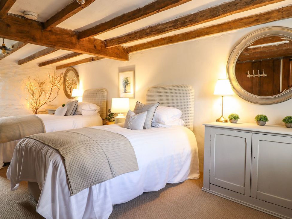 A bedroom with two beds and a nightstand at Bwthyn Canol in Llanfair