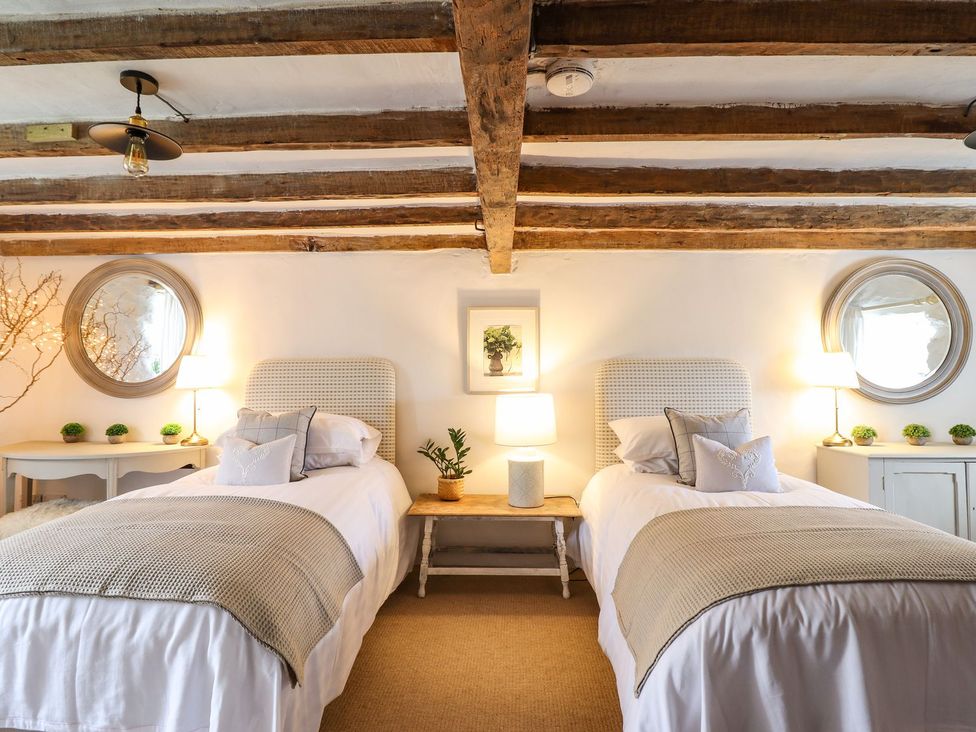 A bedroom with two beds, lamps, and a side table at Bwthyn Canol in Llanfair
