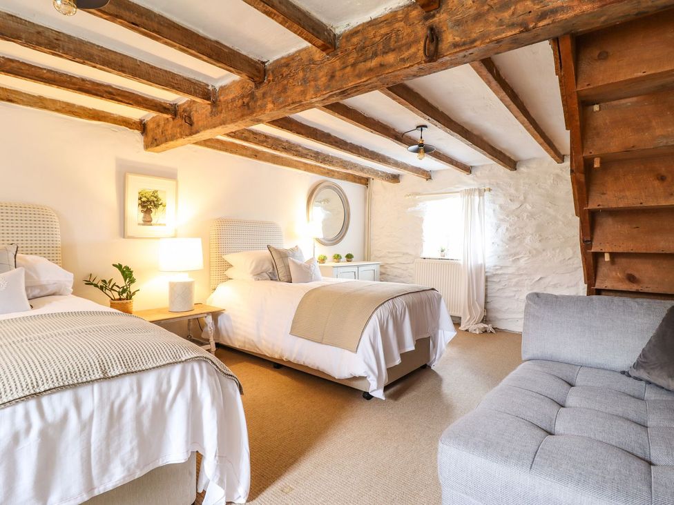 A bedroom with two beds and a staircase at Bwthyn Canol in Llanfair