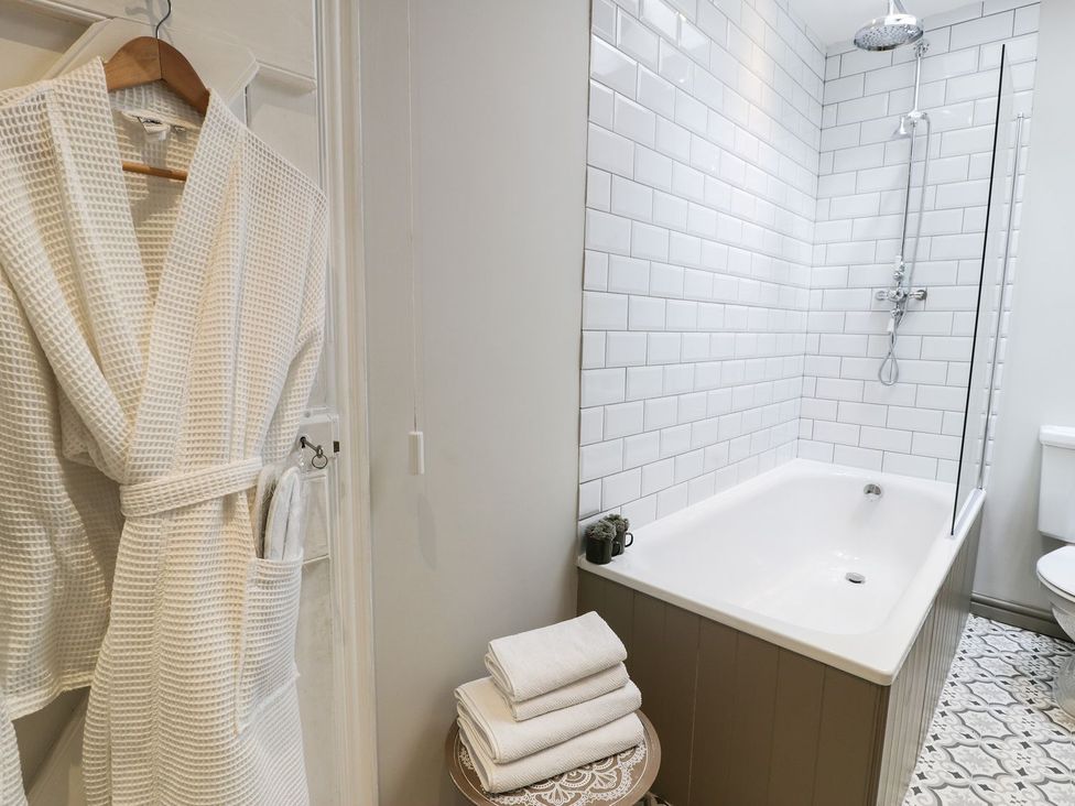A bathroom with a bath tub and shower at Bwthyn Canol in Llanfair