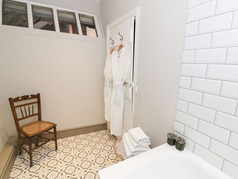 A bathroom with a bath tub and towels at Bwthyn Canol in Llanfair