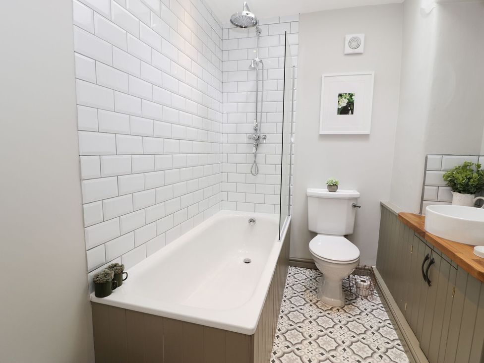 A bathroom with a bathtub, shower, toilet and sink at Bwthyn Canol in Llanfair