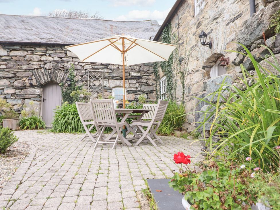 A garden with a table and chairs under an umbrella at Bwthyn Canol in Llanfair