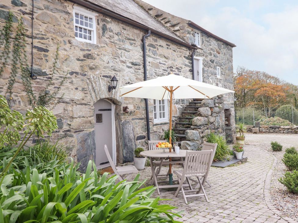 A garden area with a table and chairs under an umbrella at Bwthyn Canol in Llanfair