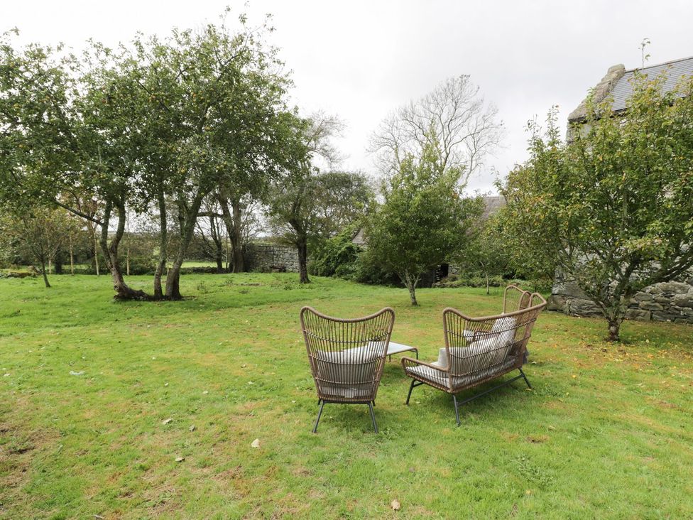 An outdoor seating area with chairs and a table at Bwthyn Canol in Llanfair