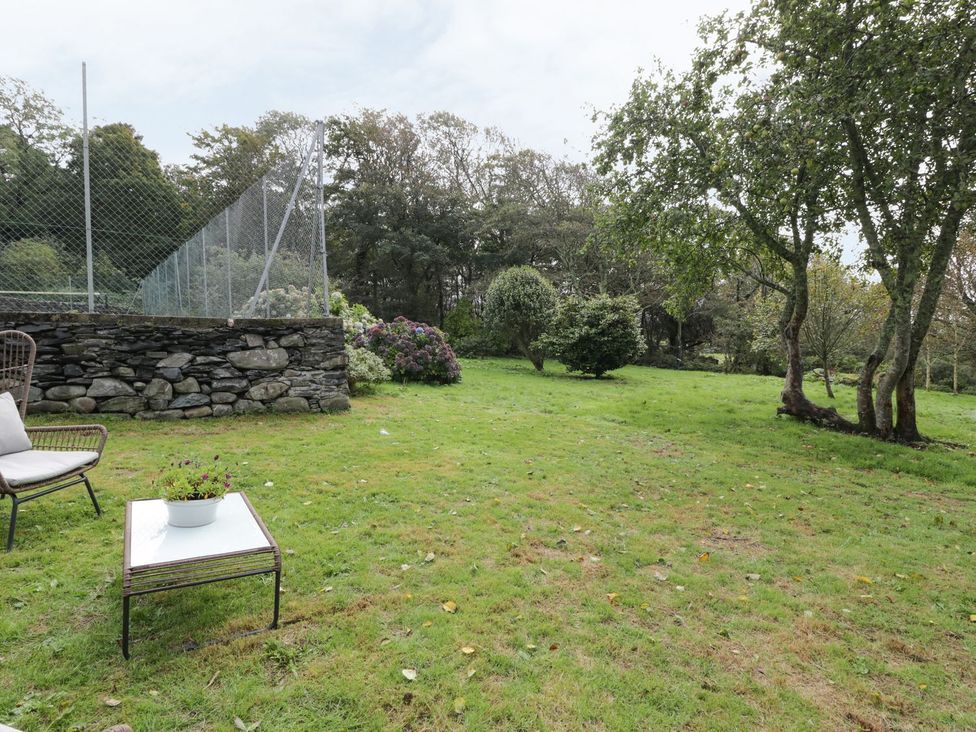 A garden area with a stone wall and seating at Bwthyn Canol in Llanfair
