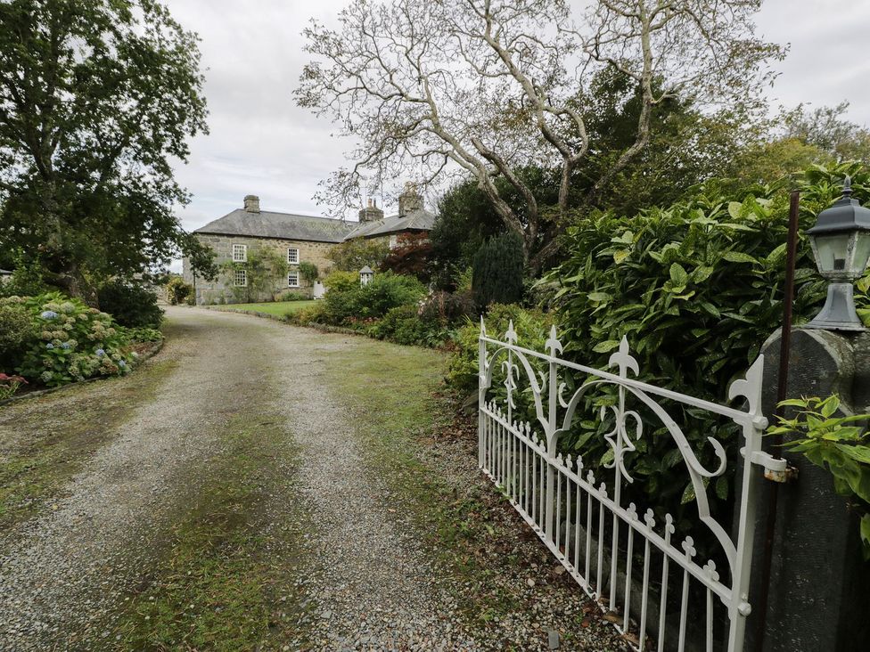 A gravel path leading to a house surrounded by trees and bushes at Bwthyn Canol in Llanfair