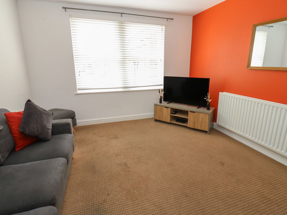 A living room with a sofa and television at Curwen Apartment in Workington
