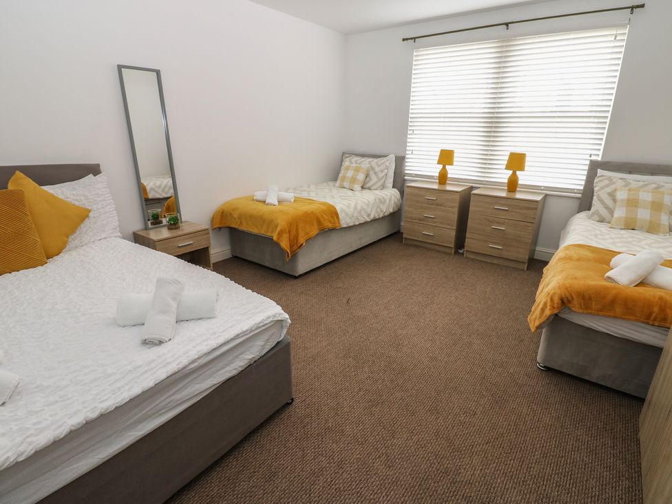 A bedroom with two single beds and one double bed at Curwen Apartment in Workington