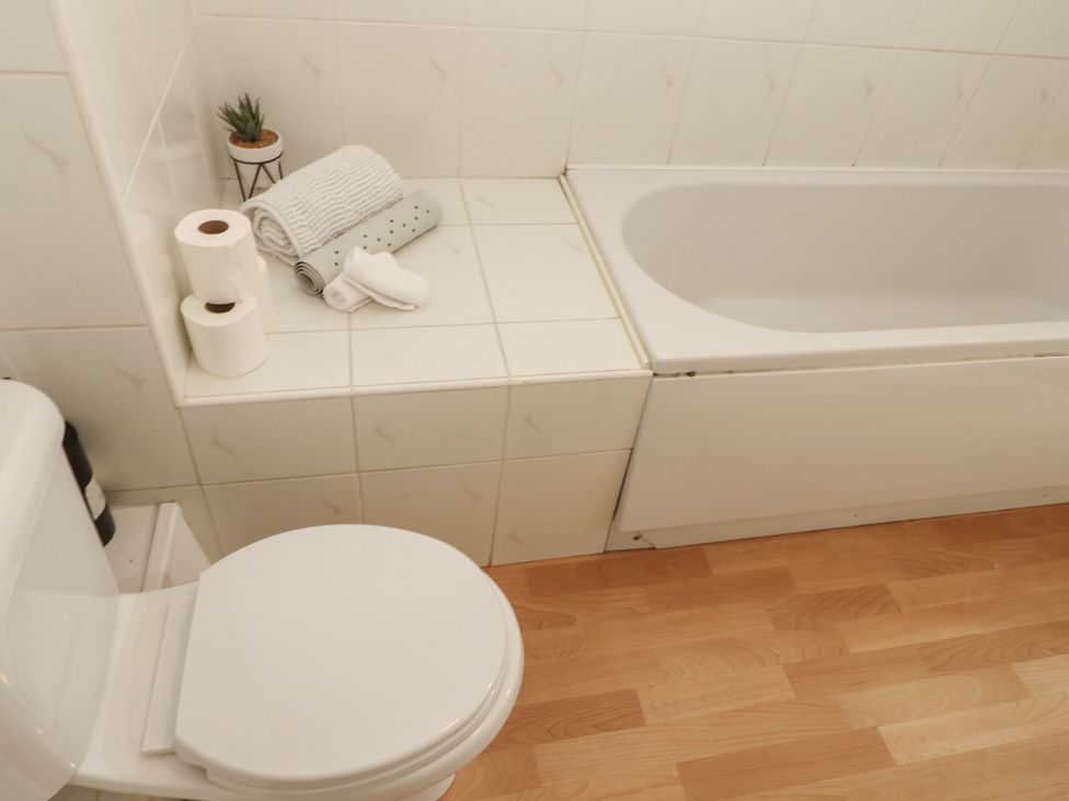 A bathroom with a toilet and bathtub at Curwen Apartment in Workington