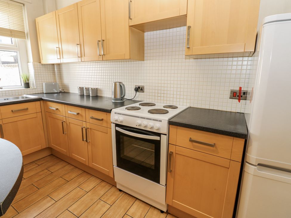A kitchen with cabinets, stove, kettle, and refrigerator at Cumberland House in Workington