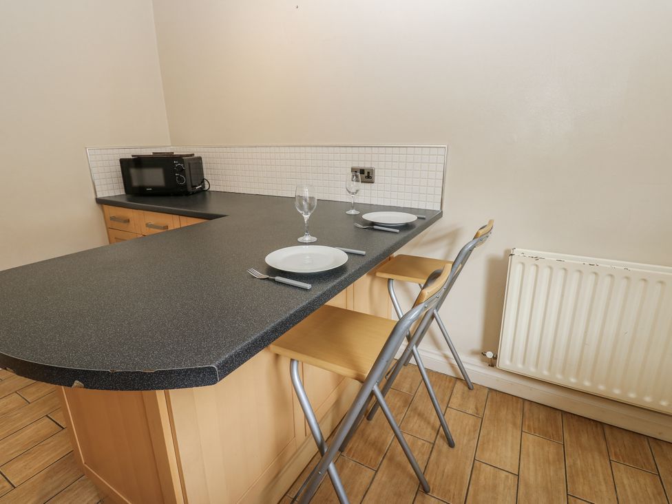 A kitchen with countertop, stools, and microwave at Cumberland House in Workington