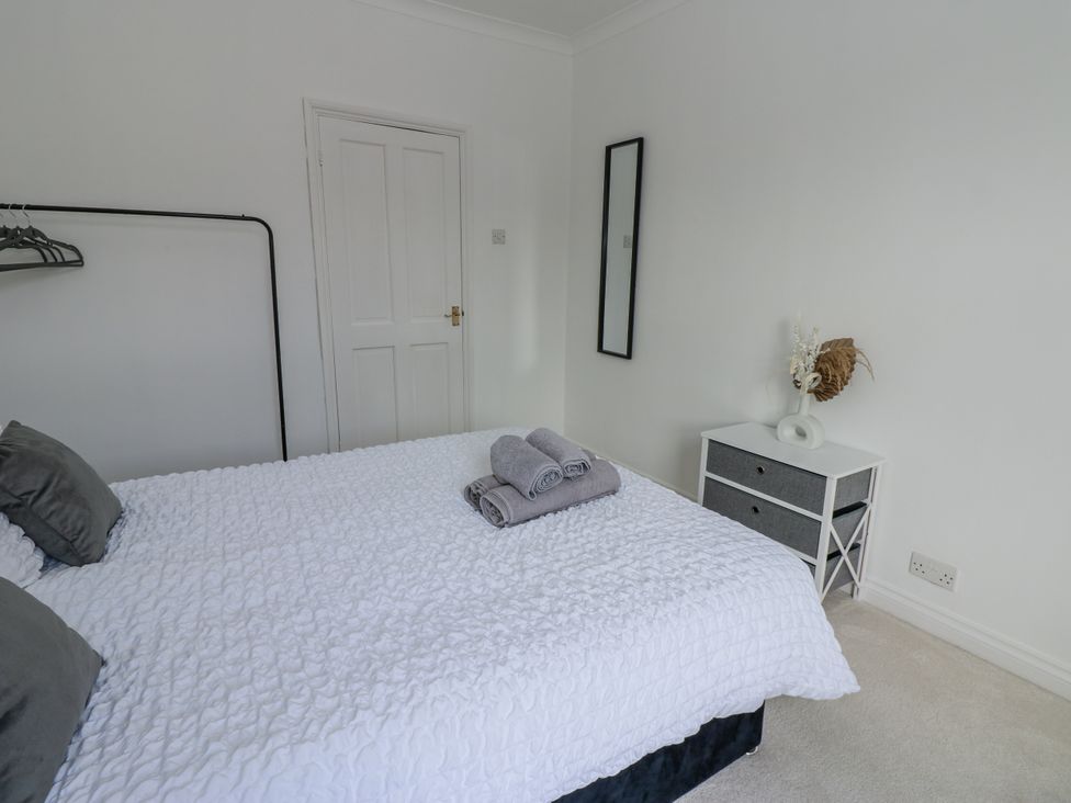 A bedroom with a bed, towels on it, and a chest of drawers at Cumberland House in Workington
