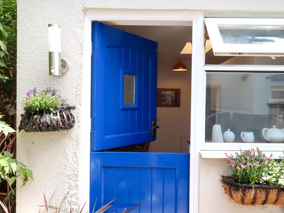 An entrance with a blue door and flower pots at Kenny Cottage in Dawlish