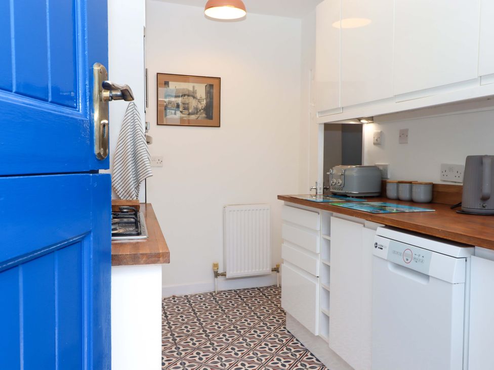 A kitchen with cabinets and appliances at Kenny Cottage in Dawlish