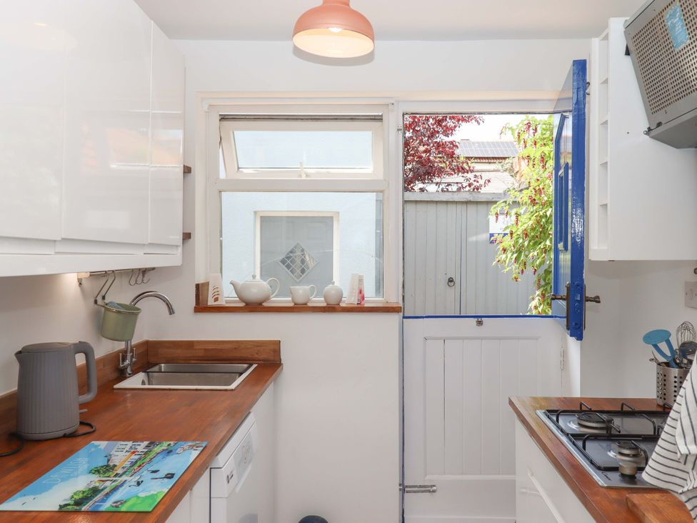 A kitchen with a sink and door leading to garden at Kenny Cottage in Dawlish