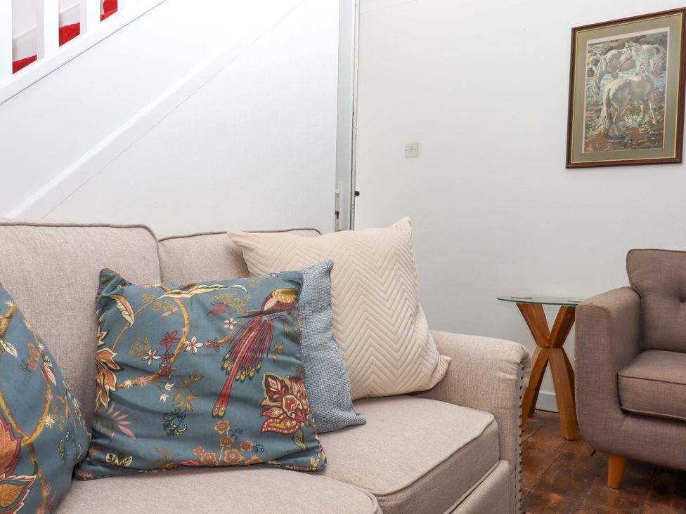 A living room with a sofa and cushions at Kenny Cottage in Dawlish