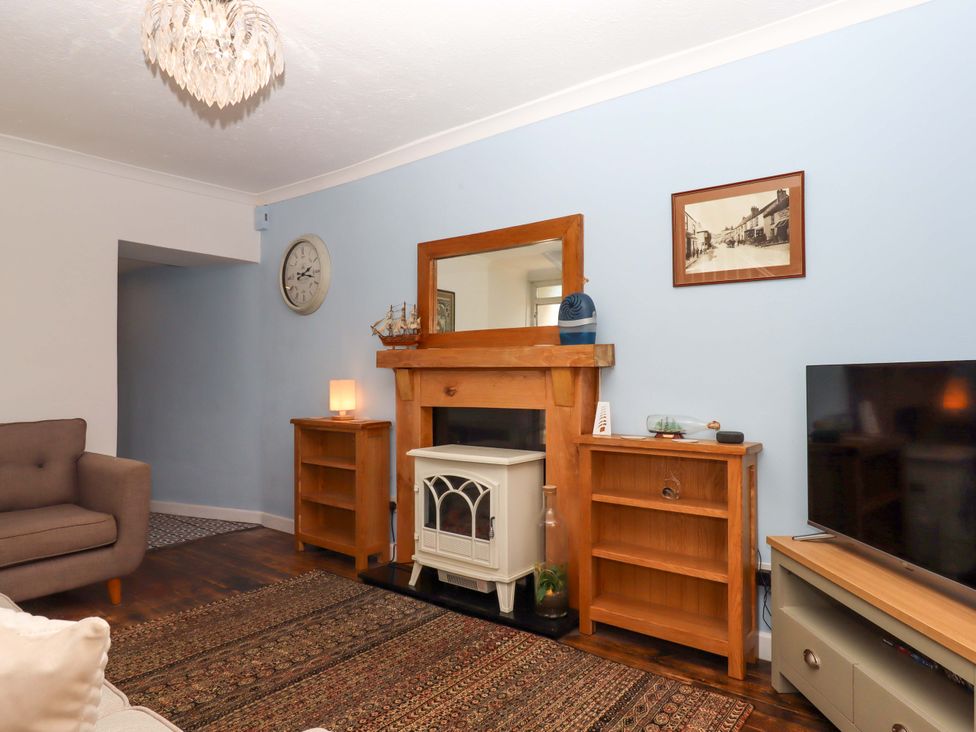 A living room with a fireplace and television at Kenny Cottage in Dawlish