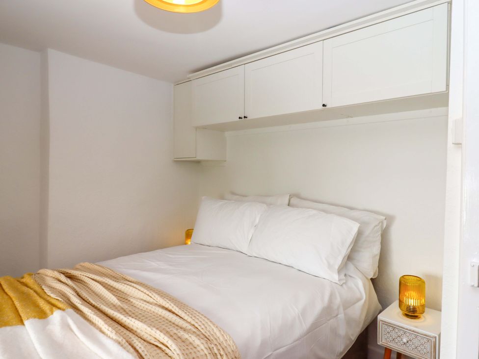 A bedroom with a bed and cabinets at Kenny Cottage in Dawlish