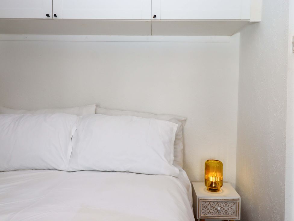 A bedroom with a bed, pillows, lamp, and nightstand at Kenny Cottage in Dawlish