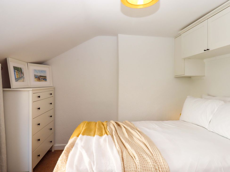 A bedroom with a bed and framed pictures at Kenny Cottage in Dawlish