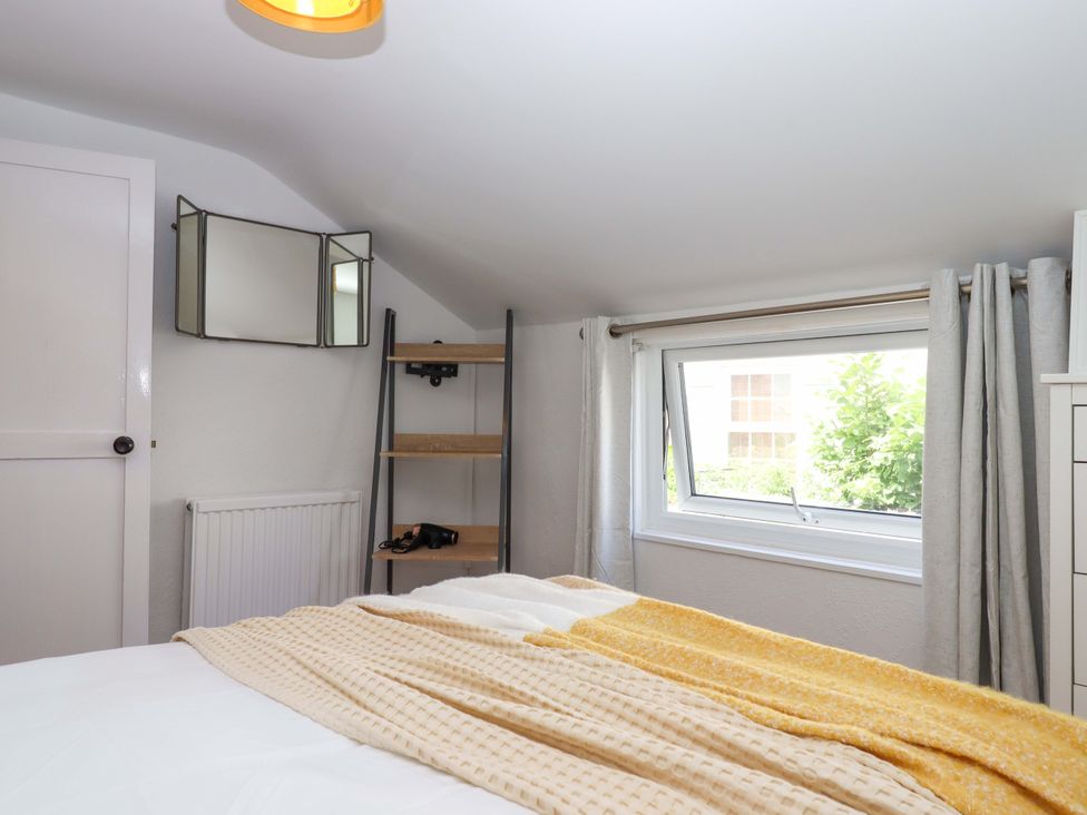 A bedroom with a bed and shelves at Kenny Cottage in Dawlish