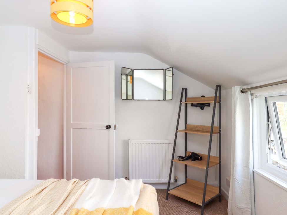 A bedroom with a mirror and shelf at Kenny Cottage in Dawlish