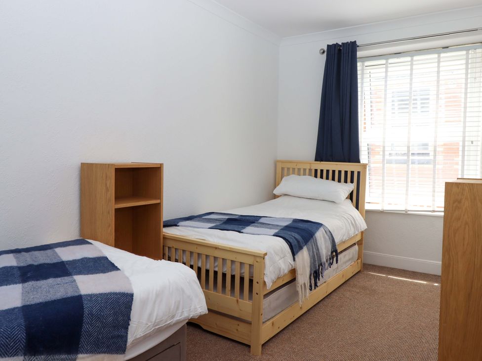 A bedroom with two beds and a bookshelf at Kenny Cottage in Dawlish