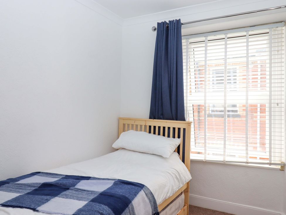 A bedroom with a bed and window at Kenny Cottage in Dawlish