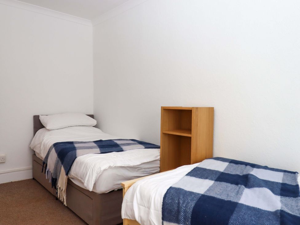 A bedroom with two beds and a shelf at Kenny Cottage in Dawlish