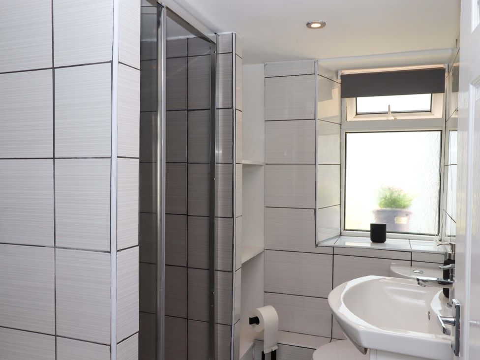 A bathroom with a shower, sink, and toilet at Kenny Cottage in Dawlish