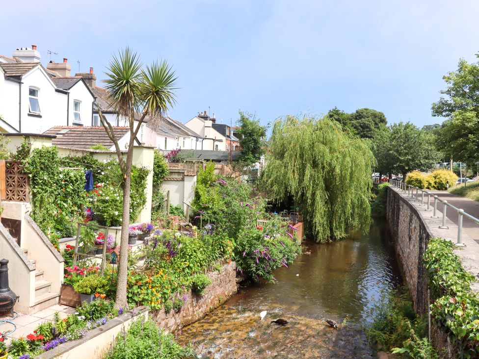 A scenic view of houses and gardens by a river at Kenny Cottage in Dawlish