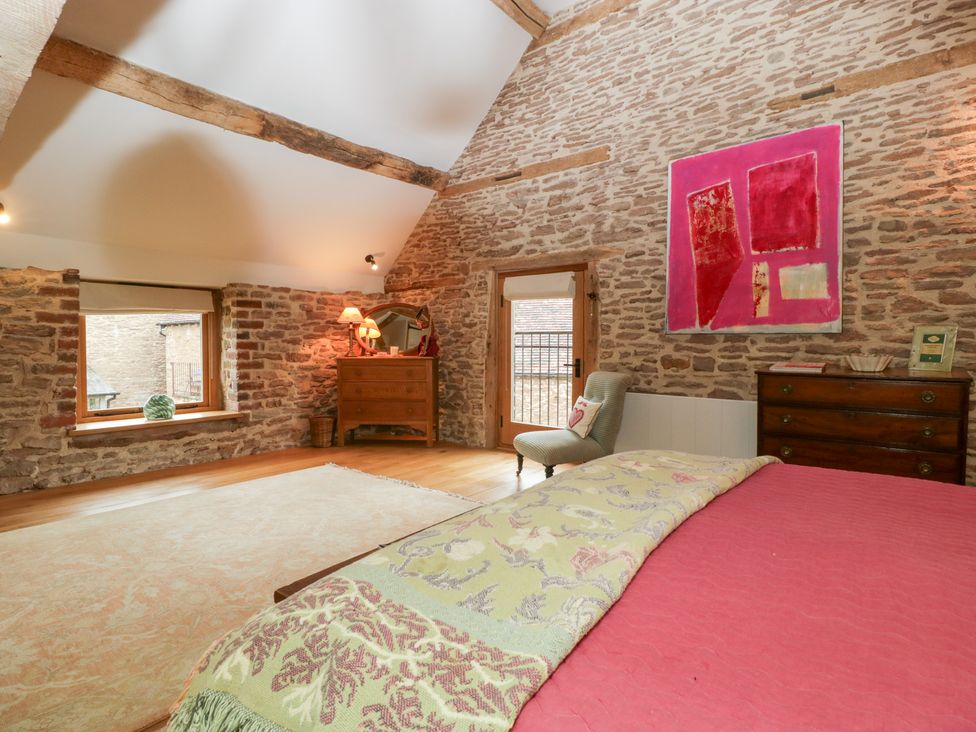 A bedroom with a bed, dresser, and armchair at The Art House in Leominster