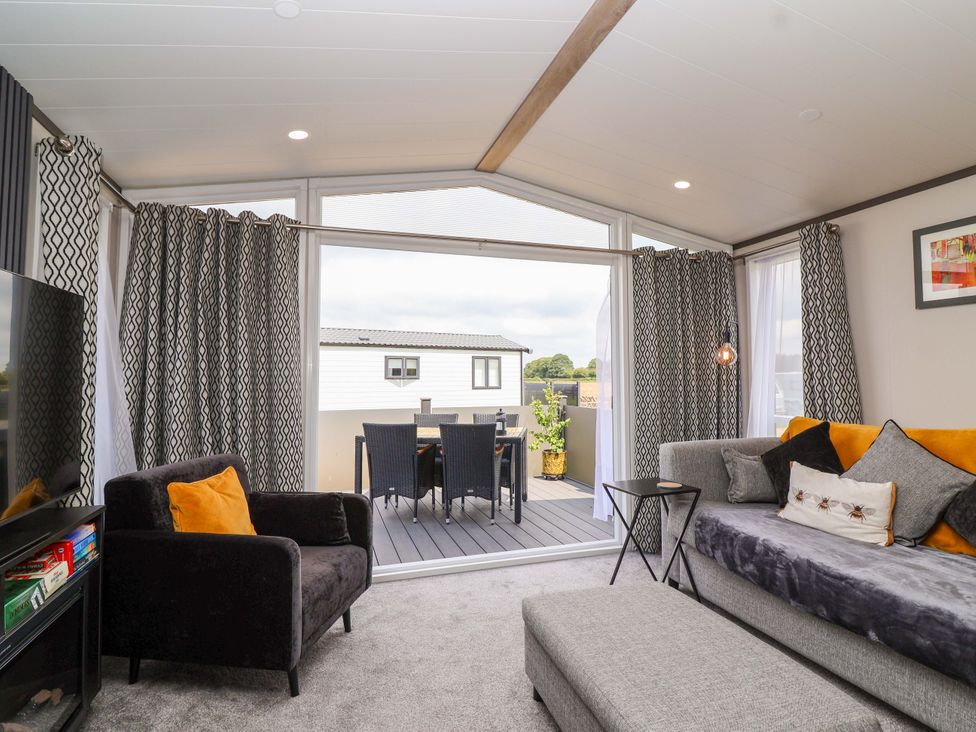 A living room with a sofa and television at Hazelnut Lodge in Chipping Norton