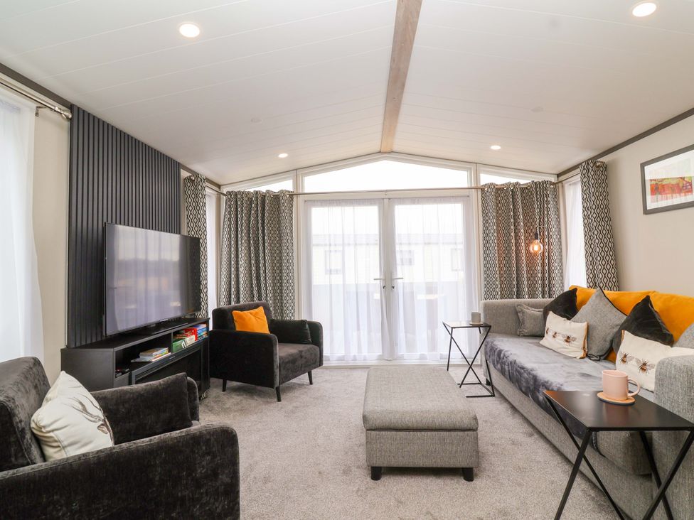 A living room with a television and sofa at Hazelnut Lodge in Chipping Norton