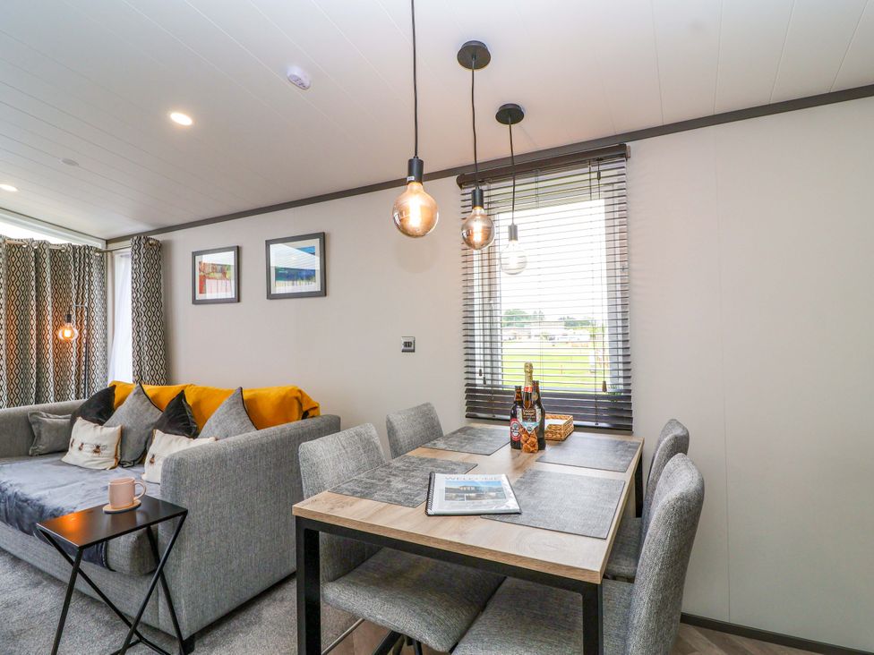 A living room with a sofa and dining area at Hazelnut Lodge in Chipping Norton
