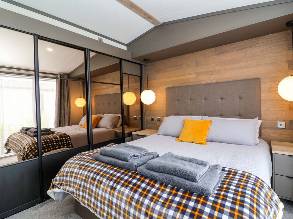 A bedroom featuring a bed with towels at Hazelnut Lodge in Chipping Norton