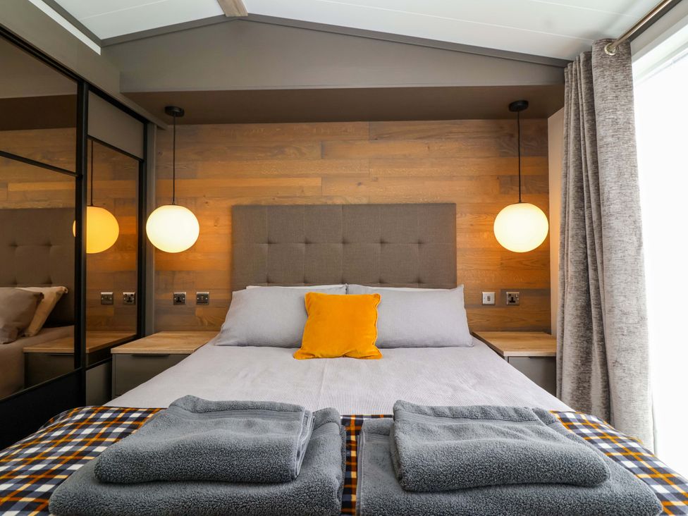 A bedroom with a bed and bedside table at Hazelnut Lodge in Chipping Norton