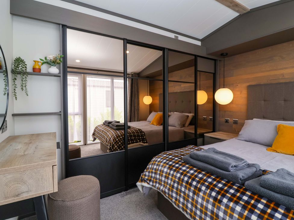 A bedroom with a bed and mirror at Hazelnut Lodge in Chipping Norton