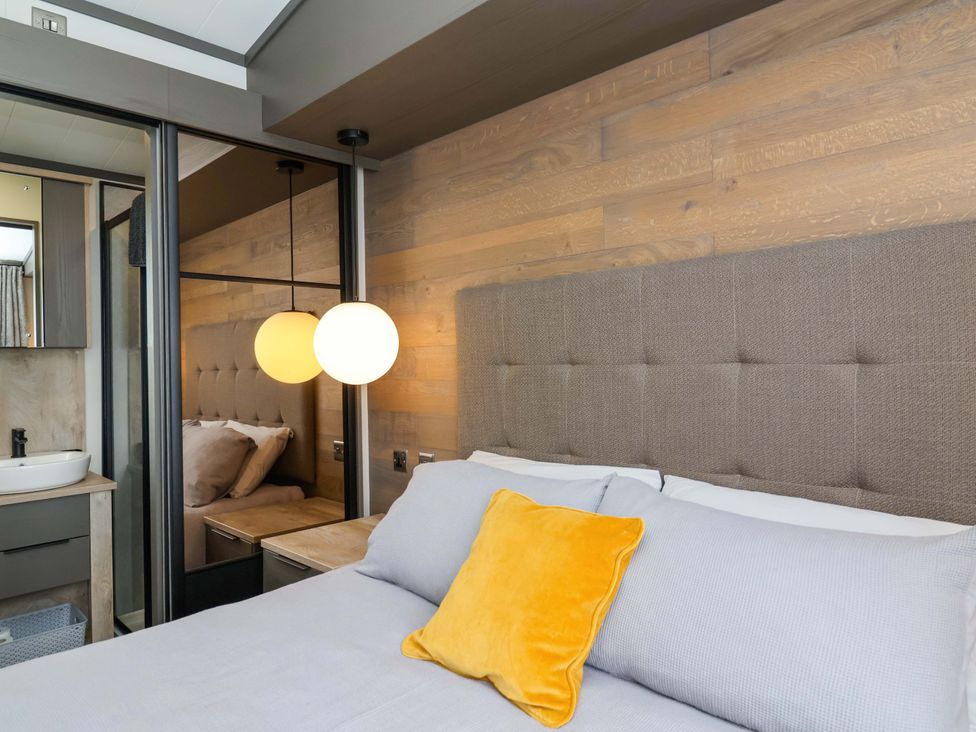 A bedroom with a bed and a lamp at Hazelnut Lodge in Chipping Norton