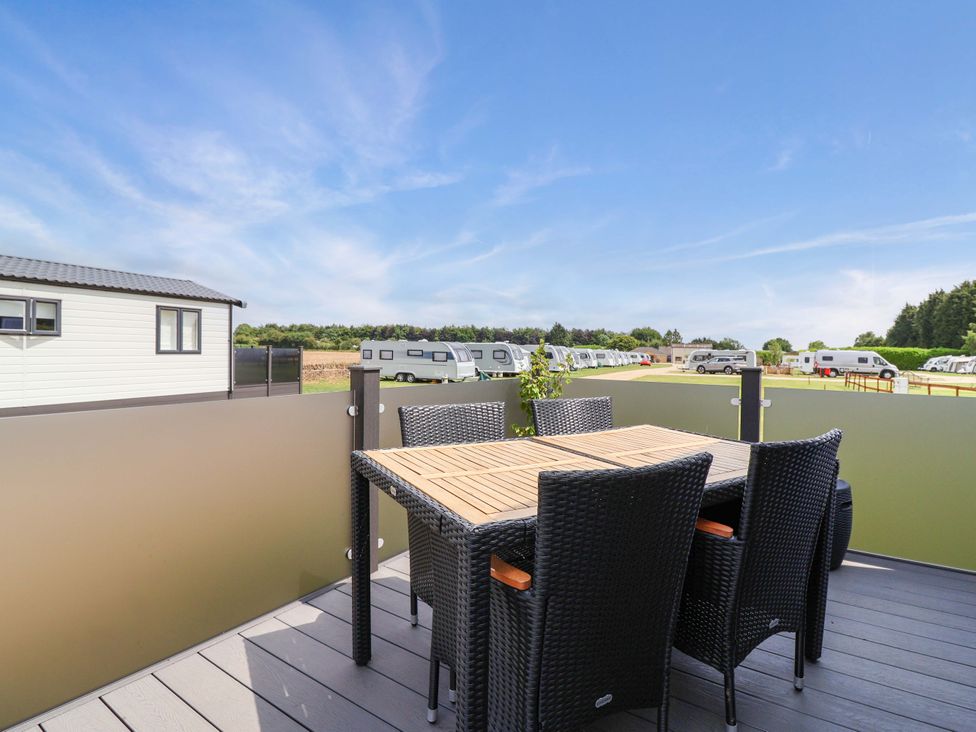 An outdoor seating area with table and chairs at Hazelnut Lodge in Chipping Norton