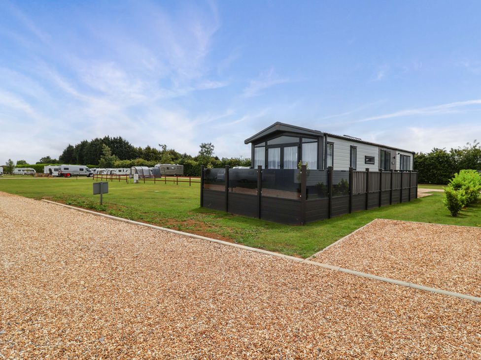 An outdoor scene with a holiday lodge and caravans at Hazelnut Lodge in Chipping Norton