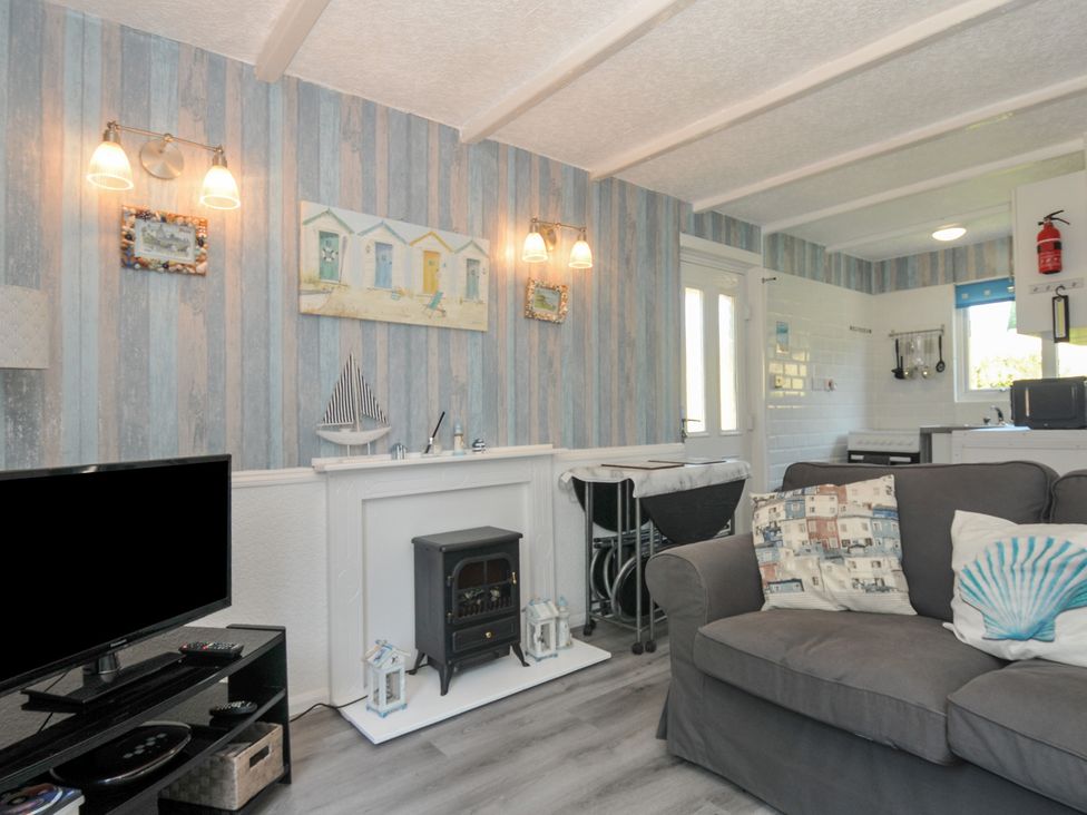 A living room with a sofa and television at 8 Hillside in Bude