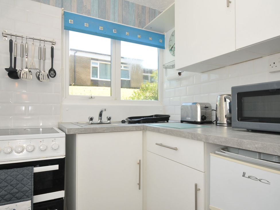 A kitchen with stove, sink and appliances at 8 Hillside in Bude