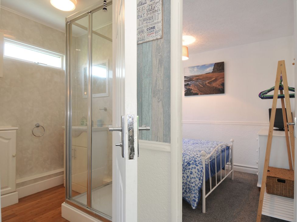 A bedroom with a bed and a shower area at 8 Hillside in Bude