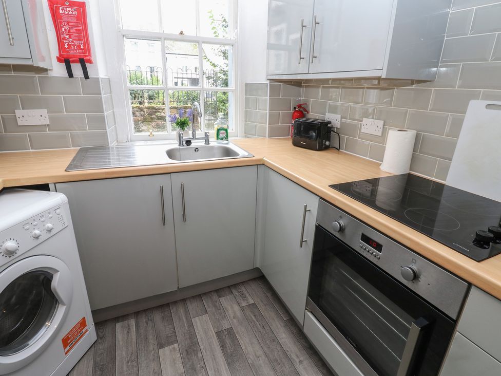 A kitchen with a sink, stove, and washing machine at Georgian Town House in Whitehaven